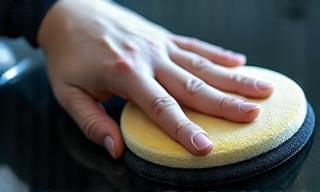 Close-up of hand applying wax to a car's paintwork